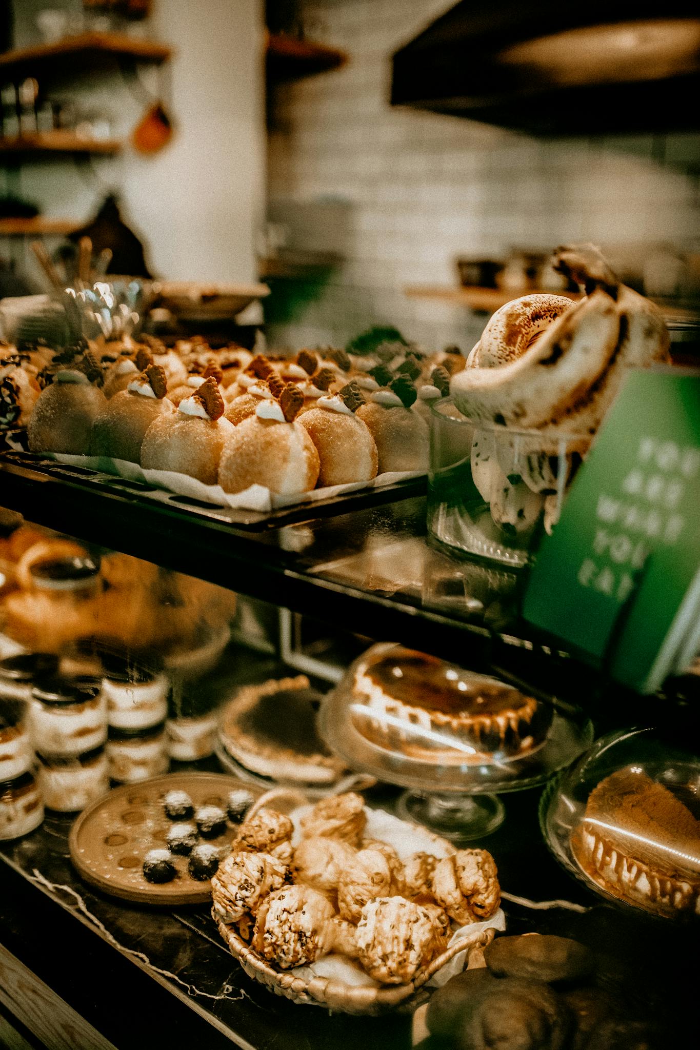 A rich display of assorted pastries and desserts in a bakery's glass counter, showcasing variety and indulgence.